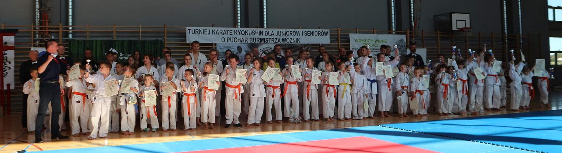 uczestnicy zawodów karate trzymający puchary i dyplomy