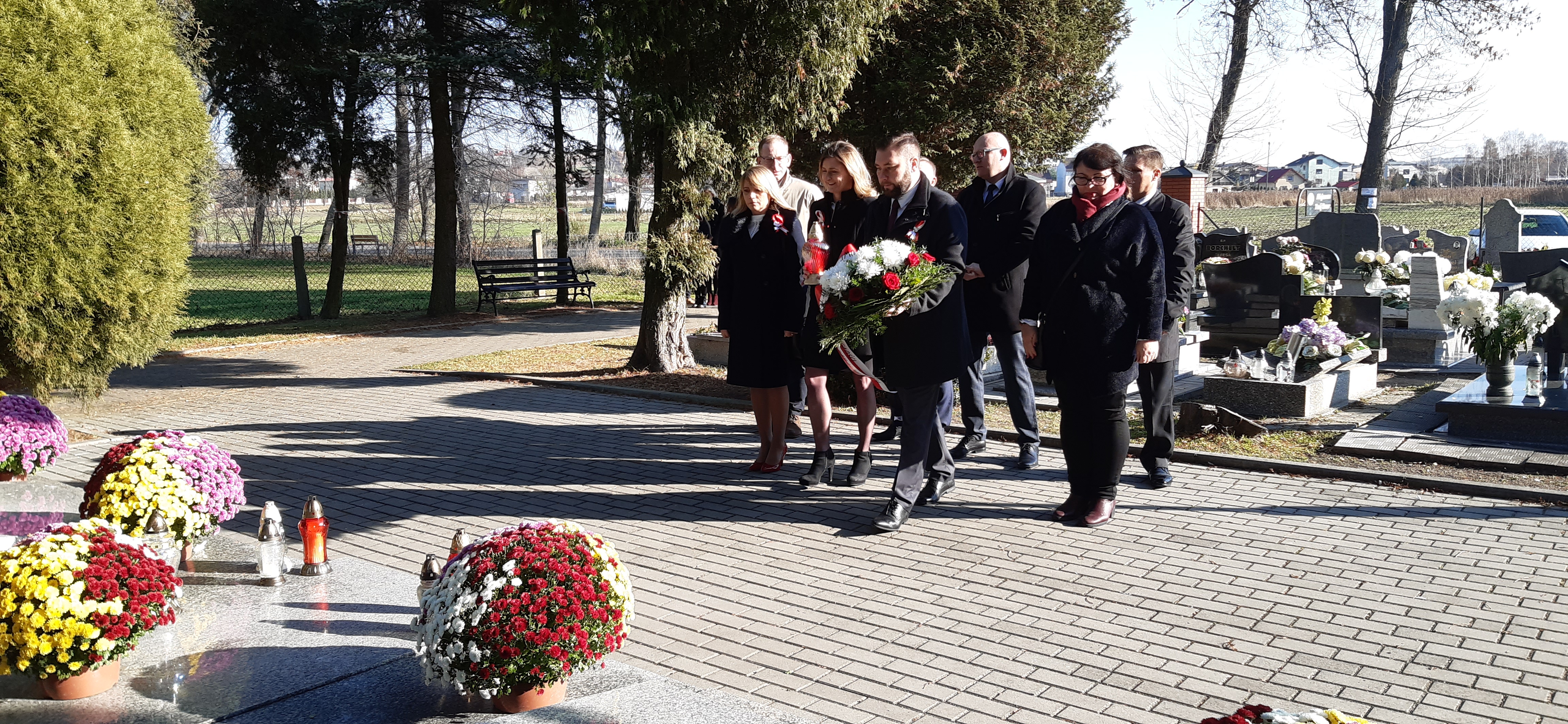 delegacja urzędu miesjkiego i rady miejskiej składa kwiaty na cmentarzu