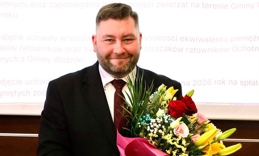 burmistrz Woźnik Michał Aloszko trzyma w rękach bukiet kwiatów